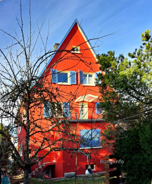 Wetterprognose März 2024 mittels der 12 Rauhnächte: rotes Haus mit blauen Fensterläden im Sonnenschein, blauer Himmel