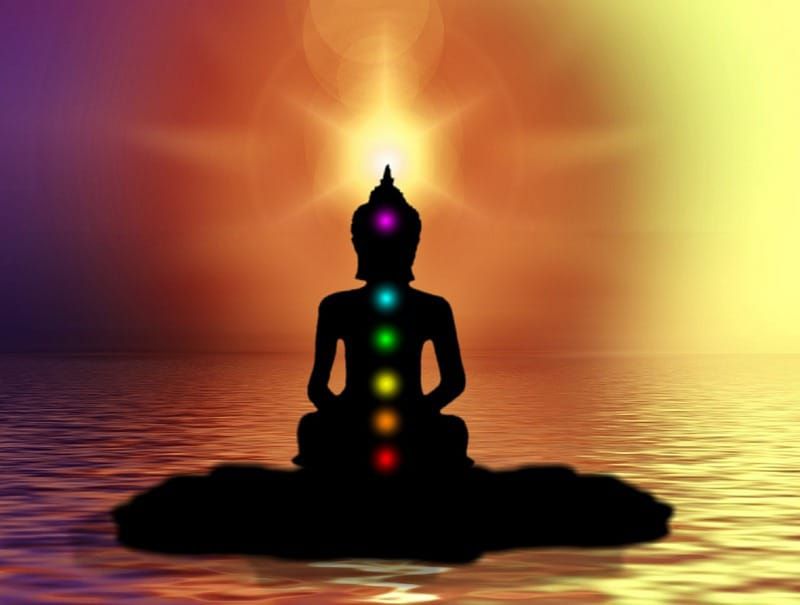 meditating Buddha with chakras lit