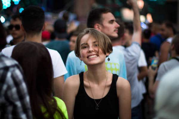 Closeup of smiling young woman in crowd - The death of identity