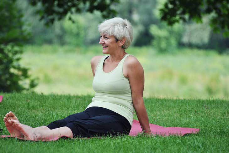 Middle-aged woman sitting on yoga mat - Yoga over 50