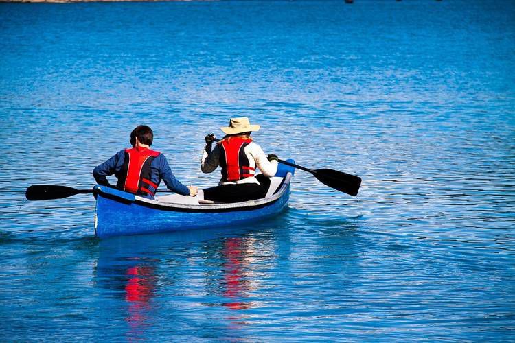 Man and woman paddling in blue canoe on lake - Philbin Pond