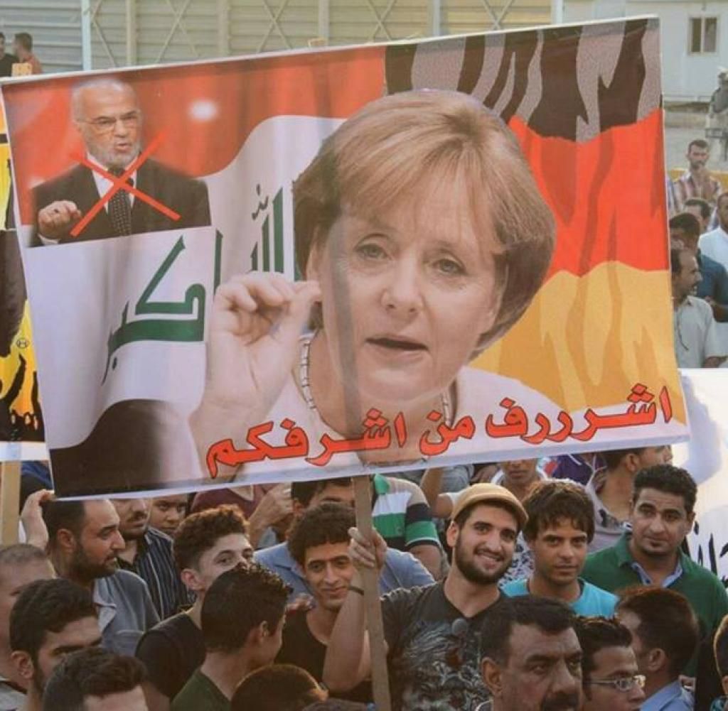 Demonstranten in Bagdad halten ein Bild von Angela Merkel hoch Unter Merkels Foto steht Sie ist besser als du und es meint den ebenfalls abgebildeten irakischen Auenminister Ibrahim al-Dschafari