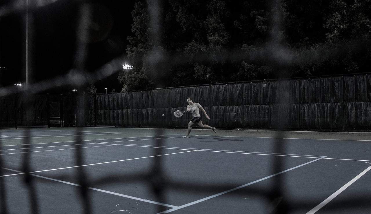 Man playing tennis in dark - The happiness challenge