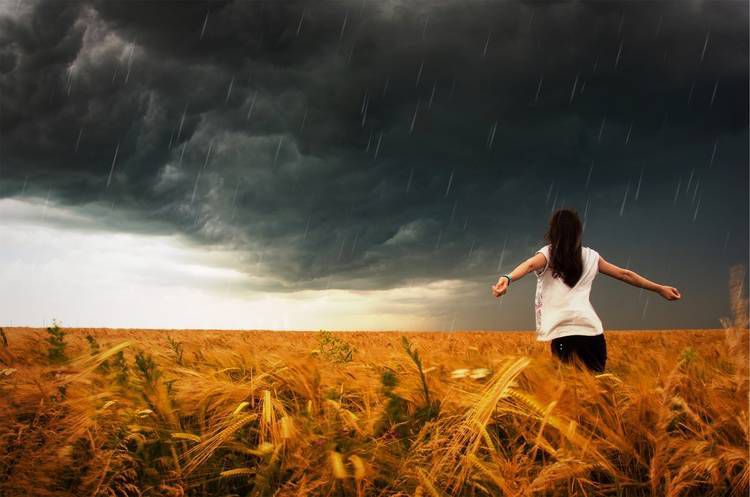 Woman with arms outstretched in stormy weather - Liberation in wanting
