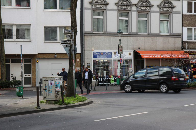 Drei Menschen laufen durch die Strae Im Hintergrund erkennt man einen trkischen Supermarkt