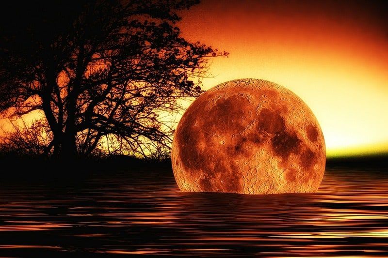Moon descending into a lake at sunset