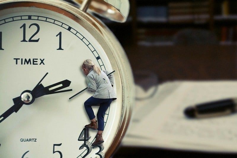 woman hanging on to he second hand of a clock