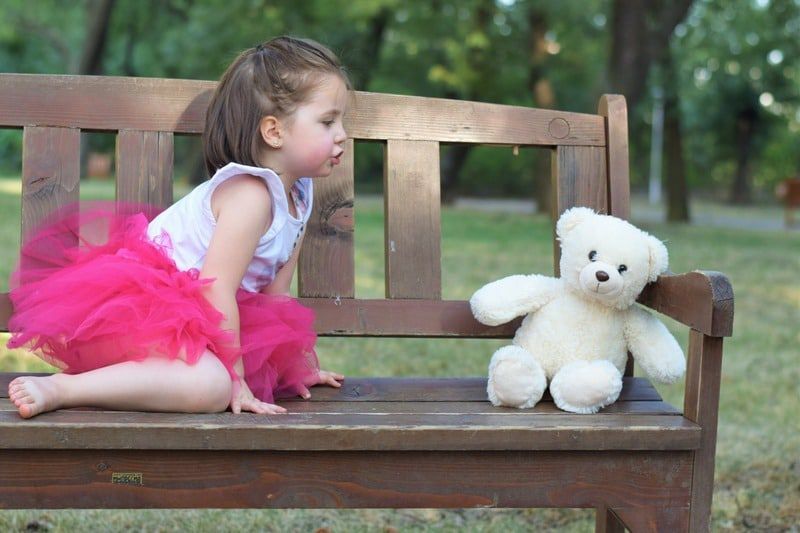 little girl talking to teddy bear