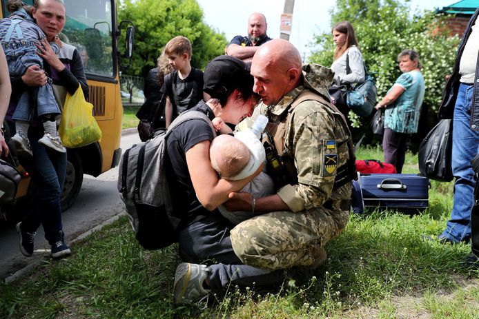 Een vrouw met een baby in de arm zoekt troost bij een Oekraense soldaat nadat ze uit een evacuatiekonvooi uit Kopiansk is gestapt