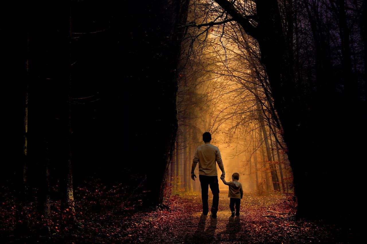 Father and son walking hand in hand on path in woods - A is for autism